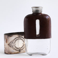 A late Victorian silver plated, shouldered glass and brown leather hip flask with a screw-cap top made by and stamped to the base "James Dickson & Sons, Sheffield".