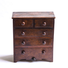 Our charming early nineteenth century little set of tabletop drawers has arched feet, an attractive apron front, and its original stained finish. It holds three fullwidth drawers and two narrow drawers, each retaining its original turned wooden knobs.