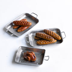 A charming collection of vintage doll's house bloomer style loaves with slashed baked tops; a set of aluminium baking / roasting pans with handles; and a fat little burnished roast chicken - all with their original painted finish, and modelled from a composition plaster material.
