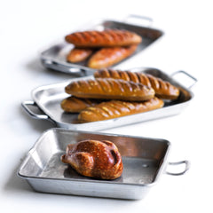 A charming collection of vintage doll's house bloomer style loaves with slashed baked tops; a set of aluminium baking / roasting pans with handles; and a fat little burnished roast chicken - all with their original painted finish, and modelled from a composition plaster material.