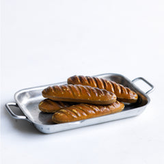 A charming collection of vintage doll's house bloomer style loaves with slashed baked tops; a set of aluminium baking / roasting pans with handles; and a fat little burnished roast chicken - all with their original painted finish, and modelled from a composition plaster material.