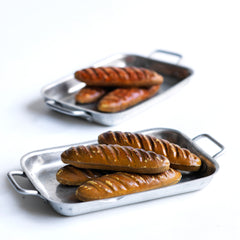 A charming collection of vintage doll's house bloomer style loaves with slashed baked tops; a set of aluminium baking / roasting pans with handles; and a fat little burnished roast chicken - all with their original painted finish, and modelled from a composition plaster material.