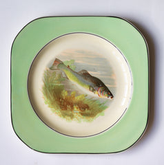 A fish pattern plate, and part of a glorious 1930s fish dinner service, complete with a large platter for serving a whole fish.  Each piece is embellished with a fresh water fish, such as pike, perch and trout, and contained within a mint-green border. Each item is stamped "Woods Ivory Ware England" to its underside.