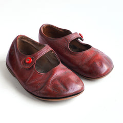 A dear little pair of vintage red leather baby's first shoes, complete with their original fastening buttons, and with leather soles, dating from 1930s - 1950.