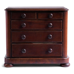 A pleasingly proportioned Victorian mini chest of drawers with rounded corners and bun feet. Comprising of three long and two short drawers, each retaining its original pair of turned wooden knobs.