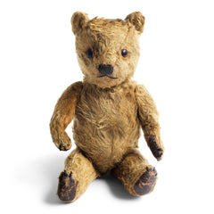 A charming and much sort after vintage 1920s teddy bear. Made from a classic shade of gold mohair, he has been much loved. His neat paw pads are made of brown leather and each has three embroidered claws. He has amber coloured eyes; his nose and mouth are embroidered; his head and arms rotate, and he has swivel jointing to his stout legs. He is stuffed with his original wood-wool fill.