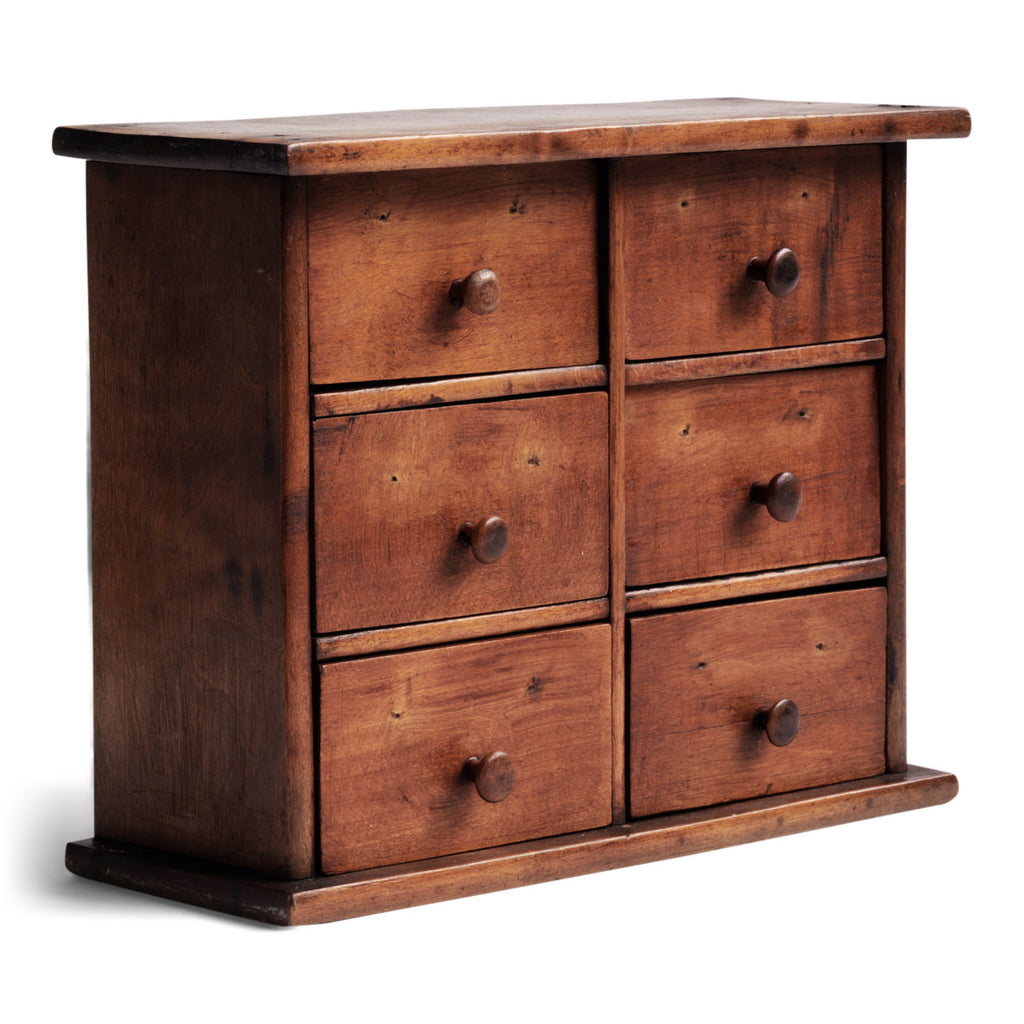 A charming mini bank of drawers in cherry wood with a pine back, comprising of six boxwood drawers, all retaining their original wooden knobs. Handy for a workshop; an office - for staples, clips and bits and bobs; for a hallway - for coins and keys; or for a dressing table - for all your magnificent jewels.
