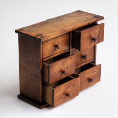 A charming mini bank of drawers in cherry wood with a pine back, comprising of six boxwood drawers, all retaining their original wooden knobs. Handy for a workshop; an office - for staples, clips and bits and bobs; for a hallway - for coins and keys; or for a dressing table - for all your magnificent jewels.