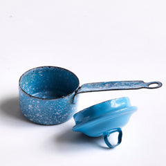 A miniature white speckled blue enamel saucepan with blue lid; a large frying pan; and a long-handled sieve. Part of an extensive antique and vintage collection of miniature pale blue enamel kitchen ware, previously owned by the miniaturist specialist and collector extraordinaire Joan Dunk.
