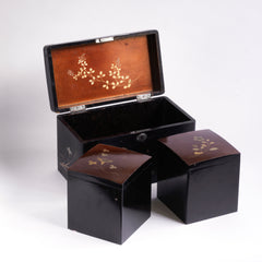A charming 1920s Japanese lacquered tea caddy inlaid with mother of pearl flowers, leaf sprigs, vine trails, and birds. The bow-topped hinged lid opens up to reveal a further two lacquered boxes with hinged lids which are removable, as shown in the images. Length 23cm Depth 12.5cm Height 14cm.