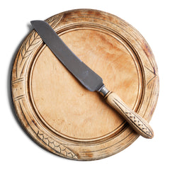 An antique bread board with matching bread knife, each carved with stylised wheat-sheaf motifs. The bread board is of sycamore, richly carved, and sits on a slightly raised foot. The knife has a wheat sheaf patterned handle with "Bread Knife" engraved on its blade; which is fitted to a stainless steel blade, marked "Butler, Sheffield, England". The knife and board have been much loved, and have a wonderful polished patina.