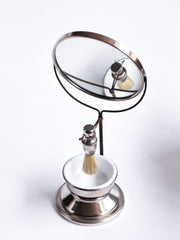 A good-looking Edwardian gentleman's shaving companion, consisting of a pivoting circular mirror set on a stand, a badger hair shaving brush and a white vitrolite glass bowl set in a nickel plated bowl-shaped stand. It was most likely made for travel, as it is light-weight and small, and therefore very transportable.