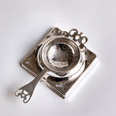 An Edwardian long-handled silver plated tea strainer with stand.  We have had this item re-silver plated, so it is in excellent condition.  Diameter strainer 6cm  Diameter of holder 9cm square  Length (handle to handle) 14.5cm