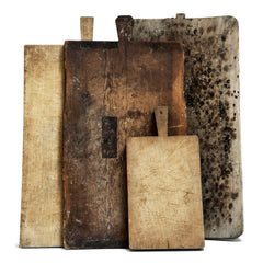 A wonderful collection of antique bread boards and chopping boards.  Their time-worn, knife-cut surfaces, some with mends and repairs, are full of character and warmth.