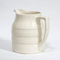 A large 1920s creamware water jug with raised banding and "Sadler England" moulded in relief to the underside of the base. 