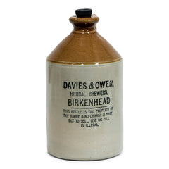 A handsome Victorian flagon with strap handle, original stopper, and bold utilitarian nineteenth century typeface: "Davies & Owen, Herbal Brewers, Birkenhead - this bottle is the property of the above and no charge is made, but to sell, use or fill is illegal".