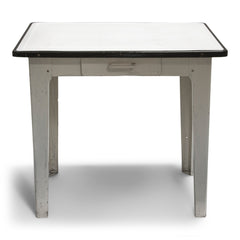 A good-looking mid-century enamel topped kitchen table. The white enamel top has a black enamel rim, and is carried on an off-white painted steel frame fitted with a single drawer and tapering steel legs.