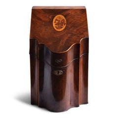 A handsome George III mahogany veneered knife box with a flower basket oval inlay on its slanting lid; a serpentine front banded in satinwood; and a compass star decoration with rope cross-banded inlay applied to the underside of its lid. The base is felt baize covered, and it has a copper escutcheon and lid pull.
