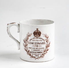 An Edwardian Edward VII coronation mug with tin white glaze by Royal Dolton, made to commemorate his coronation in 1902. "Long life and happiness King Edward VII and his beloved consort Queen Alexandra crowned June 26th 1902" amid a crown of oak and laurel leaves illustrates the rear; and a portrait of Edward VII and Queen Mary and "E R" decorates the main body of the mug - along with flags, a lion, a unicorn and swags of roses.