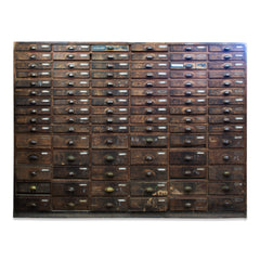 An exceptional bank of 90 wooden workshop drawers with original patina and finish. Each drawer has a cup-shaped metal pull handle and a name-plate holder; the lower, deeper drawers are singular inside, whereas the upper slimmer drawers contain divisions.