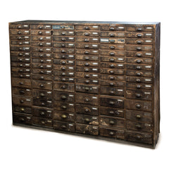 An exceptional bank of 90 wooden workshop drawers with original patina and finish. Each drawer has a cup-shaped metal pull handle and a name-plate holder; the lower, deeper drawers are singular inside, whereas the upper slimmer drawers contain divisions.