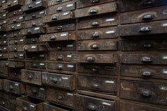 An exceptional bank of antique wooden workshop drawers with original patina and finish. Each of the 90 drawers has a cup-shaped metal pull handle and a name-plate holder; the lower, deeper drawers are singular inside, whereas the upper slimmer drawers contain divisions.