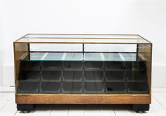 A rare high quality 1930s Art Deco shop counter fitted with eighteen Bakelite display drawers and brass frame to its vitrine. It has oak veneer panelled sides and front with black painted Art Deco stepped feet mounted on ball castors – so it can be moved with absolute ease.  The maker and shopfitters nameplate ‘Courtney Pope Ltd of London N15’ is secured to the inside front of the cabinet, and each Bakelite drawer is beautifully monogrammed with the initials CP in a striking 1930s modernist font. 