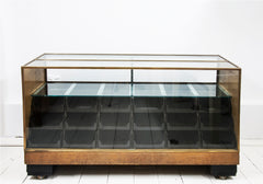 A rare high quality 1930s Art Deco shop counter fitted with eighteen Bakelite display drawers and brass frame to its vitrine. It has oak veneer panelled sides and front with black painted Art Deco stepped feet mounted on ball castors – so it can be moved with absolute ease.  The maker and shopfitters nameplate ‘Courtney Pope Ltd of London N15’ is secured to the inside front of the cabinet, and each Bakelite drawer is beautifully monogrammed with the initials CP in a striking 1930s modernist font.
