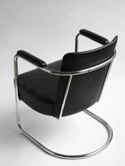 An elegant and rare tubular steel modernist armchair attributed to PEL (Practical Equipment Ltd) with continuous tubular chrome frame and horseshoe cantilever base. The chromium plated steel wraps around the back and forms the armrests, and it is upholstered in its original black leatherette.