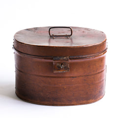 A handsome Victorian hat tin with hinged lid, carrying handle, hasp, and original pecan brown painted finish. The interior paint is also original and is a steely Prussian blue. It has a wonderful polished and buffed patina, built from its 130 years of travels.