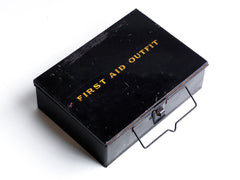 A good-looking 1920s first aid tin, the lid stencilled "First Aid Outfit". It has a carrying handle and fastening hasp, and it has its original black enamel paint finish.