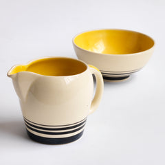 A Susie Cooper 1930s kestrel shape milk jug and sugar bowl in Cooper's classic art deco Yellow Tango pattern. Each piece is stamped to the underside "Susie Cooper Production Crown Works Burslem" and bears the Susie Cooper leaping deer trademark. 