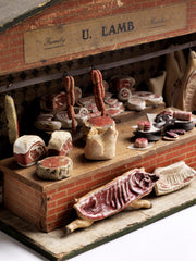 Antique butcher’s shop diorama with its original signage “U. Lamb” and “Family Butcher”. It is complete with counter, papered tiling, butcher’s blocks, butcher’s scales, and various composition cuts, sides and joints of meat – including strings of sausages and a pig’s head.