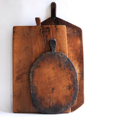 A wonderful collection of antique and vintage bread boards. Their time-worn, knife-cut surfaces are full of character and warmth. They make excellent communal serving platters for air dried ham, antipasto, breads, cheeses, and pickles; and when not in use, look great as a backdrop when propped up on the kitchen side.