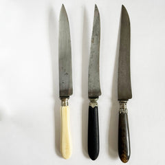 Late 19th century French carving knives with carbon steel blades: one with a real bone handle; another with a dark stained wooden handle: and a third with a real horn handle.