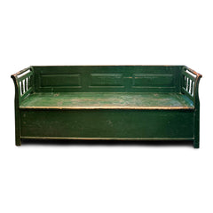 A late 19th century Romanian box bench with its original green painted finish, and a hinged seat that opens to reveal ample storage. It has a panelled back, and its twin arms are supported by turned spindles.