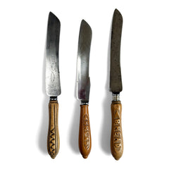 A collection of antique bread knives with carved sycamore and beech handles, and carbon steel engraved blades - two with "Bread" carved on their handles. 