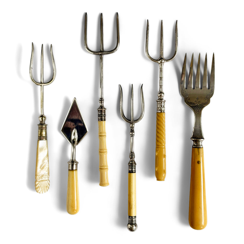 A collection of antique bread and pickle forks, along with a rare butter trowel. All have Stirling silver mounts and silver plated tines.
