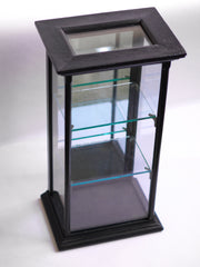 A beautifully proportioned late 19th century table-top ebonised display cabinet with glass on three sides, and with a window of glass on top - so that its contents could be lit from above. It has an elegant plinth base, a top with stepped entablature, and is fitted with three removable glass shelves. The hinged back is fitted inside with a full length mirror that is gently foxed, and it is opened and closed using a brass pull-catch. 