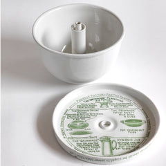 A vintage ironstone Grimwades pudding bowl with central heat funnel and fitted lid. The bowl and lid are liberally decorated with graphic typography and illustrations on how to use the Quick Cooker.