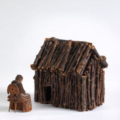 A miniature naive carved wooden figure of a peasant women seated on an Alpine chair, with its original staining and paint - mid century, Bavarian. And a miniature house made of twigs.