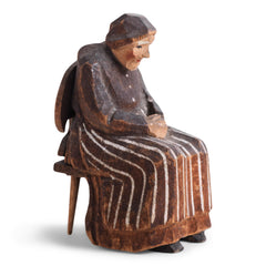 A miniature naive carved wooden figure of a peasant women seated on an Alpine chair, with its original staining and paint - mid century, Bavarian.