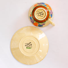 Back-stamps to a Clarice Cliff early Autumn Crocus Athens cup and saucer with vivid paintwork and boldly executed crocuses, and with early hand painted green "Crocus" stamp on the underside along with "Hand painted Bizarre by Clarice Cliff, Newport Pottery England". 