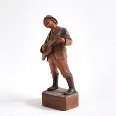 An early twentieth century carved wooden figure of a jovial musician playing a guitar, most likely from Bavaria or the Black Forest, Germany. 