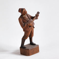 An early twentieth century carved wooden figure of a jovial musician playing a guitar, most likely from Bavaria or the Black Forest, Germany. 