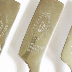 Detail of a knife blade in a rare set of 6 vintage bone handle scone knives each blade marked "Frederick Reynolds" alongside an engraved tea cup and saucer motif.