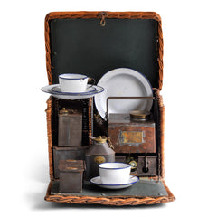An antique automobilia "En Route" motor car tea basket by Sirram dating to 1910 - 1920: a complete travelling picnic set in white enamel and steel, with brass detailing; each and every carefully designed piece pleasingly housed and stowed in its steel and wicker lined compartments, ready for its travels. The front pulls down to reveal a handy work-station, a fitted vulcanised cardboard tray in racing-car green, where all things for a picnic can be assembled. 