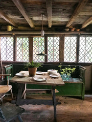 A late 19th century Romanian box bench with its original green painted finish, and a hinged seat that opens to reveal ample storage. It has a panelled back, and its twin arms are supported by turned spindles.