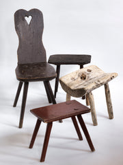 A vintage Romanian alpine folk art style stick-leg chair with high back and charming heart detail, and three rustic stools.