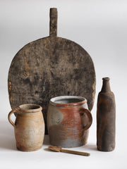 A collection of vintage French rustic earthenware confit pots in greys, beiges and browns, and a sculptural matt moleskin brown ceramic calvados bottle. 